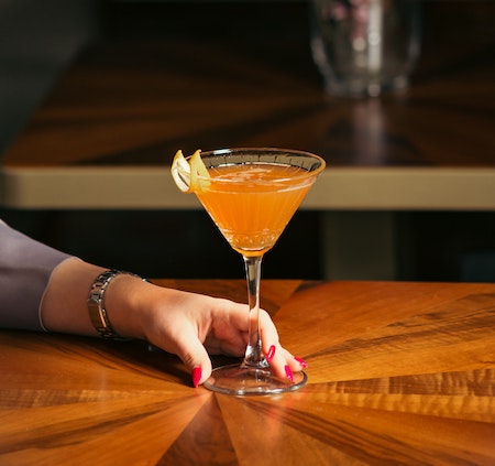 fancy cocktail in hand on table